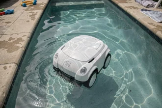 Robot nettoyeur automatique se déplaçant au fond d'une piscine familiale vue de dessus avec reflets d'eau