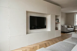 Meuble TV en placo avec défauts de finition visibles : joints mal lissés et télévision mal centrée dans une niche murale de salon moderne